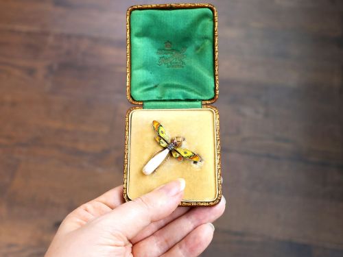 fig 3. An antique late Victorian dragonfly brooch crafted in yellow gold with yellow enamel wings, garnet eyes, rose-cut diamond accents, and a elongated natural pearl abdomen.