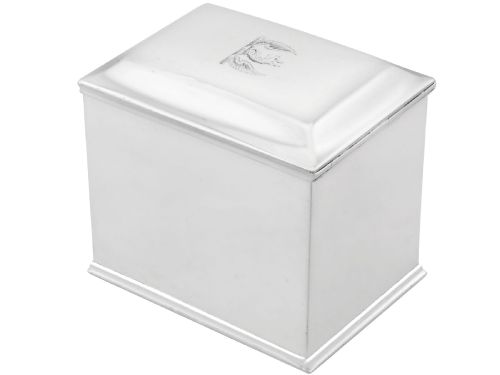 fig 1. A rectangular George III sterling silver tea caddy featuring a fitted cover engraved with a heraldic crest and stepped moulded borders along the base and top.