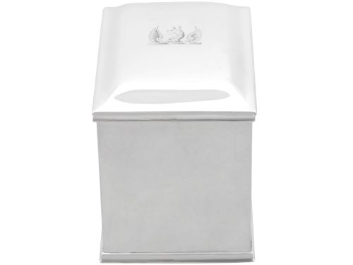 fig 2. A rectangular George III sterling silver tea caddy featuring a fitted cover engraved with a heraldic crest and stepped moulded borders along the base and top.