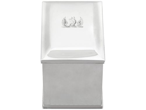 fig 3. A rectangular George III sterling silver tea caddy featuring a fitted cover engraved with a heraldic crest and stepped moulded borders along the base and top.