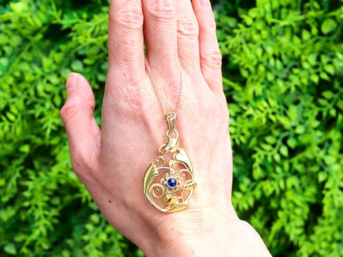 fig 1. An openwork Art Nouveau 14ct yellow gold pendant featuring botanical leaf motifs surrounding a central bezel-set blue sapphire.