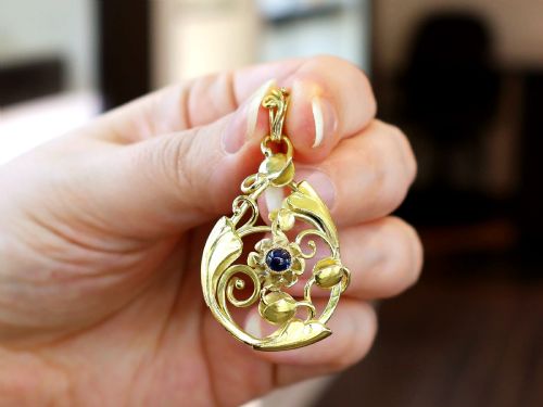 fig 2. An openwork Art Nouveau 14ct yellow gold pendant featuring botanical leaf motifs surrounding a central bezel-set blue sapphire.