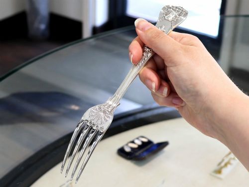 fig 4. A collection of ornate sterling silver cutlery pieces featuring intricately embossed handles and polished bowls, including ladles, forks, knives, and spoons.