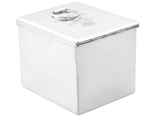 fig 1. A rectangular Victorian sterling silver tea caddy featuring an engraved crest, top folding handle, and visible side hallmarks.