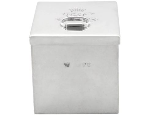 fig 2. A rectangular Victorian sterling silver tea caddy featuring an engraved crest, top folding handle, and visible side hallmarks.