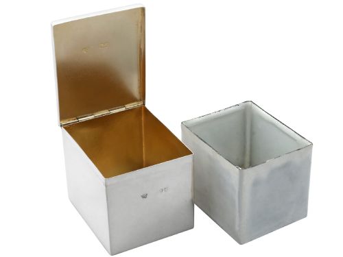 fig 5. A rectangular Victorian sterling silver tea caddy featuring an engraved crest, top folding handle, and visible side hallmarks.