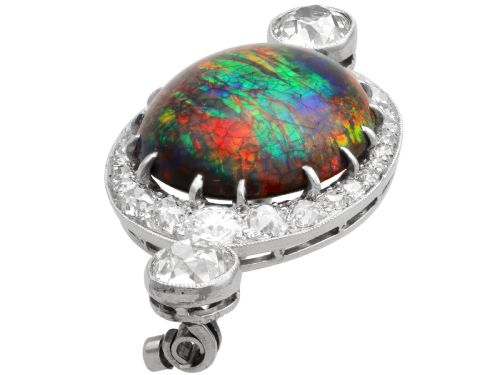 fig 5. An Edwardian platinum brooch featuring an oval cabochon boulder opal surrounded by a halo of diamonds and two outer accent diamonds.