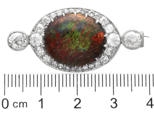 fig 8. An Edwardian platinum brooch featuring an oval cabochon boulder opal surrounded by a halo of diamonds and two outer accent diamonds.