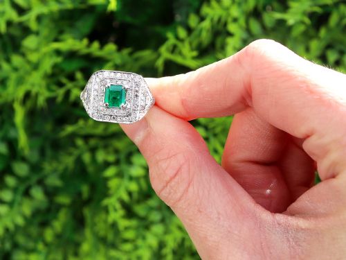 fig 1. An Art Deco platinum ring featuring a central square green emerald surrounded by geometric concentric halos of brilliant-cut diamonds.
