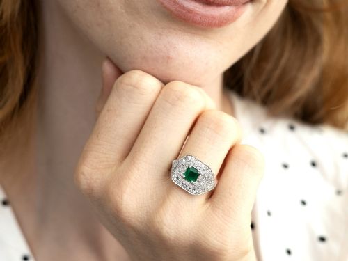 fig 2. An Art Deco platinum ring featuring a central square green emerald surrounded by geometric concentric halos of brilliant-cut diamonds.
