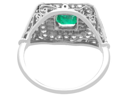 fig 5. An Art Deco platinum ring featuring a central square green emerald surrounded by geometric concentric halos of brilliant-cut diamonds.