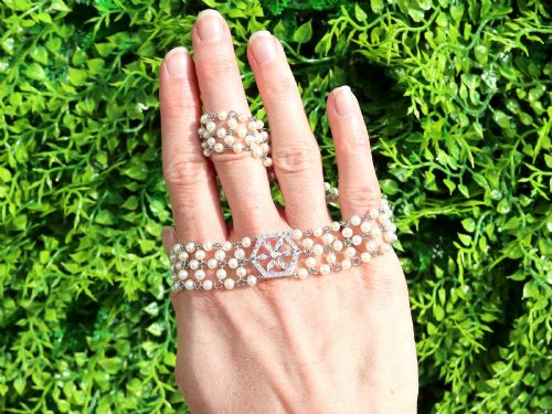 fig 1. A multi-strand white pearl choker necklace joined at the front by an 18ct white gold hexagonal plaque set with small diamonds.