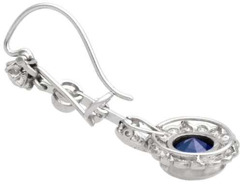 fig 6. A pair of antique Art Deco platinum drop earrings featuring round dark blue sapphires encircled by diamond halos suspended from articulated diamond links.