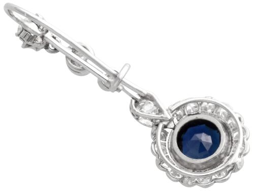 fig 7. A pair of antique Art Deco platinum drop earrings featuring round dark blue sapphires encircled by diamond halos suspended from articulated diamond links.