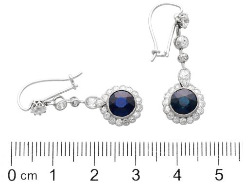 fig 8. A pair of antique Art Deco platinum drop earrings featuring round dark blue sapphires encircled by diamond halos suspended from articulated diamond links.