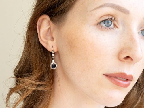 fig 9. A pair of antique Art Deco platinum drop earrings featuring round dark blue sapphires encircled by diamond halos suspended from articulated diamond links.