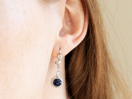 fig 10. A pair of antique Art Deco platinum drop earrings featuring round dark blue sapphires encircled by diamond halos suspended from articulated diamond links.
