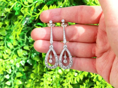 fig 1. A pair of Art Deco platinum drop earrings featuring openwork teardrop frames set with diamonds and geometric articulated tops.