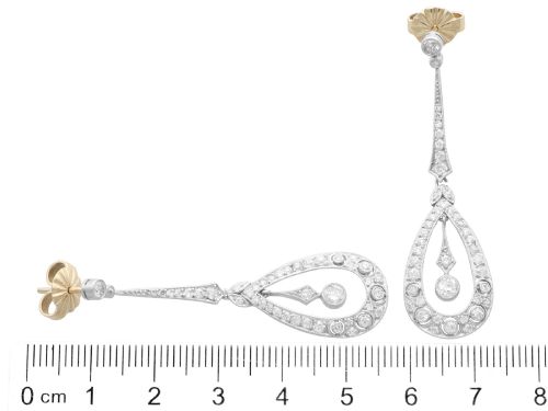 fig 6. A pair of Art Deco platinum drop earrings featuring openwork teardrop frames set with diamonds and geometric articulated tops.