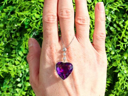 fig 1. An antique heart-cut purple amethyst pendant framed with a millegrain edge and suspended beneath three round diamond accents set in gold.
