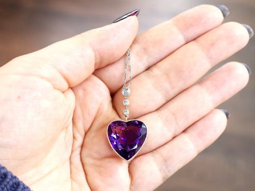 fig 2. An antique heart-cut purple amethyst pendant framed with a millegrain edge and suspended beneath three round diamond accents set in gold.