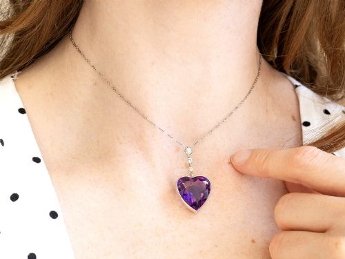 fig 6. An antique heart-cut purple amethyst pendant framed with a millegrain edge and suspended beneath three round diamond accents set in gold.