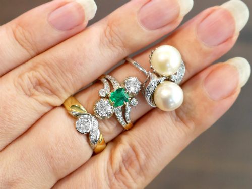 fig 3. An antique 18ct yellow gold twist ring set with a central green emerald, flanked by two old cut diamonds and diamond-set shoulders.