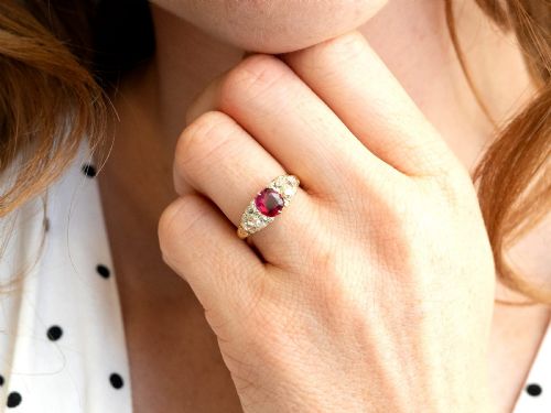 fig 2. An 18ct yellow gold dress ring featuring a central cushion-cut red ruby flanked by old cut diamonds with carved scrollwork setting.