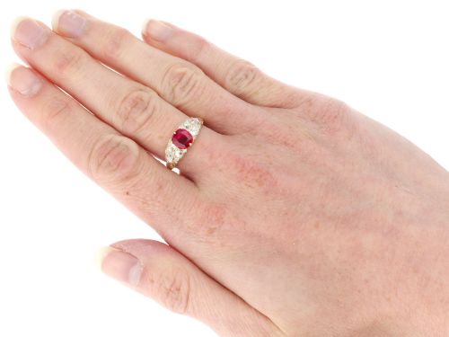fig 7. An 18ct yellow gold dress ring featuring a central cushion-cut red ruby flanked by old cut diamonds with carved scrollwork setting.