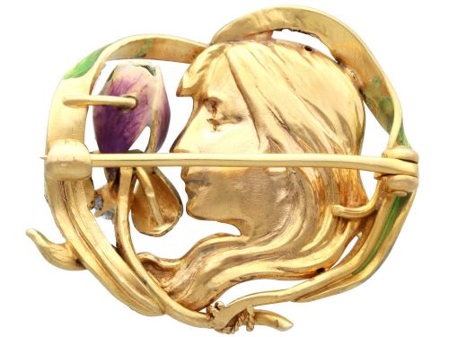 fig 7. An Art Nouveau 18ct yellow gold brooch detailing a maiden profile framed by green enamel foliage and a purple enamelled iris set with a single diamond.