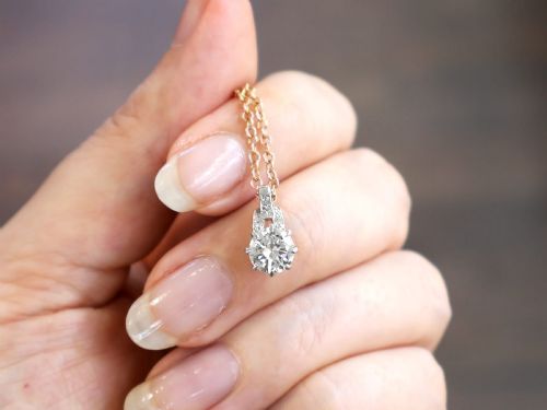 fig 2. An antique platinum solitaire pendant featuring a round diamond in a claw setting suspended from a fine gold chain.