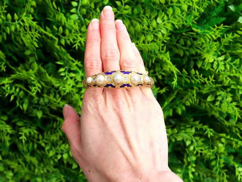 fig 1. A Victorian hinged yellow gold bangle featuring detailed hand engraving, deep blue enamel panels, set diamonds, and graduated natural pearls.