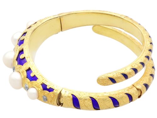 fig 7. A Victorian hinged yellow gold bangle featuring detailed hand engraving, deep blue enamel panels, set diamonds, and graduated natural pearls.