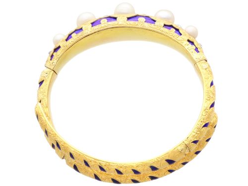 fig 9. A Victorian hinged yellow gold bangle featuring detailed hand engraving, deep blue enamel panels, set diamonds, and graduated natural pearls.