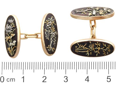 fig 6. A pair of late nineteenth-century double-ended oval cufflinks crafted in 18ct yellow gold, featuring dark patinated shakudo panels with gold and silver botanical relief inlays.