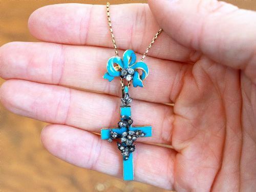 fig 2. A Georgian 15ct yellow gold cross pendant featuring blue enamel, a diamond-set ribbon bow loop, and floral diamond overlays.