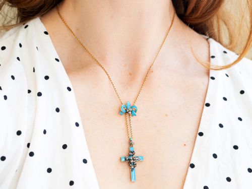 fig 4. A Georgian 15ct yellow gold cross pendant featuring blue enamel, a diamond-set ribbon bow loop, and floral diamond overlays.