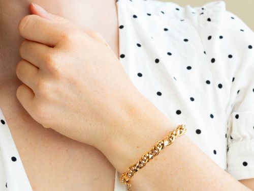 fig 4. An antique Edwardian 15ct gold hinged bangle featuring a twisted ribbon design intertwined around a row of polished gold beads, fitted with a safety chain.