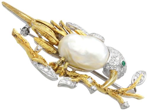 fig 6. An antique 14ct gold bird brooch featuring a blister pearl body, pave diamond head with an emerald eye, perched on a textured gold branch.
