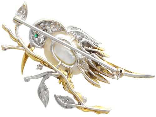 fig 7. An antique 14ct gold bird brooch featuring a blister pearl body, pave diamond head with an emerald eye, perched on a textured gold branch.