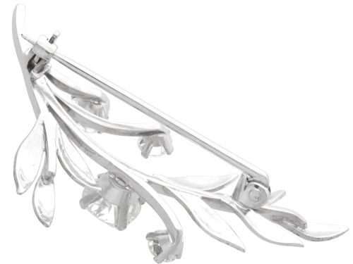 fig 5. An 18ct white gold brooch crafted in the shape of a flowering spray, featuring leaf motifs and claw-set diamonds.