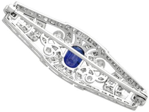 fig 6. An Art Deco 9ct white gold brooch featuring a central oval blue sapphire framed by geometric openwork set with round diamonds.