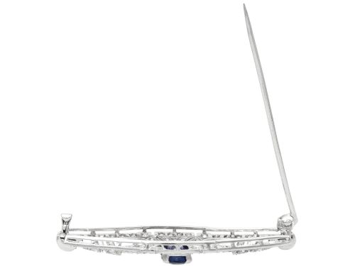fig 7. An Art Deco 9ct white gold brooch featuring a central oval blue sapphire framed by geometric openwork set with round diamonds.