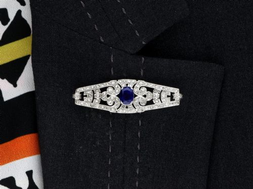 fig 9. An Art Deco 9ct white gold brooch featuring a central oval blue sapphire framed by geometric openwork set with round diamonds.