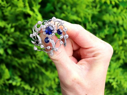 fig 1. An Edwardian 18ct white gold brooch set with three oval blue sapphires surrounded by openwork diamond-set scrollwork.