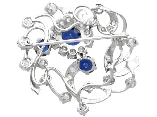fig 6. An Edwardian 18ct white gold brooch set with three oval blue sapphires surrounded by openwork diamond-set scrollwork.