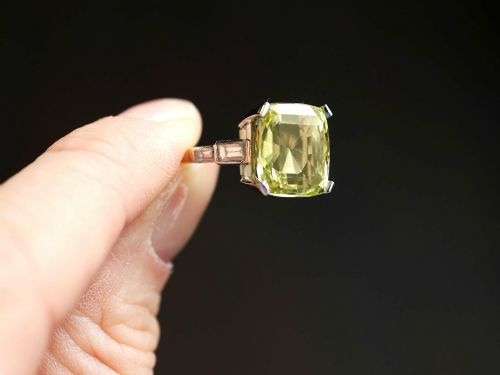 fig 3. An Art Deco platinum ring featuring a large cushion cut yellow chrysoberyl central gemstone flanked by step cut diamonds on the shoulders.