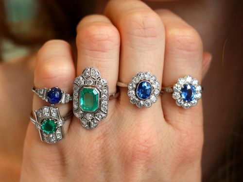 fig 4. An antique platinum cluster ring featuring a central oval blue sapphire framed by twelve round cut diamonds with millegrain detail.
