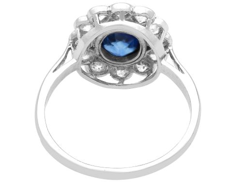 fig 6. An antique platinum cluster ring featuring a central oval blue sapphire framed by twelve round cut diamonds with millegrain detail.