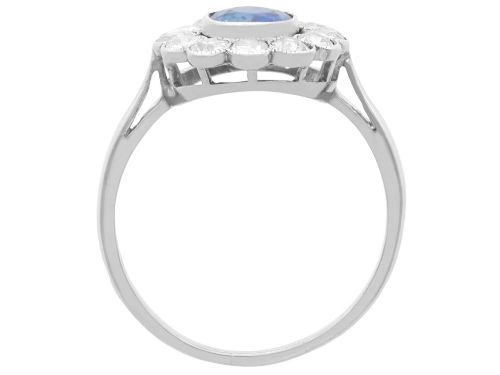 fig 7. An antique platinum cluster ring featuring a central oval blue sapphire framed by twelve round cut diamonds with millegrain detail.